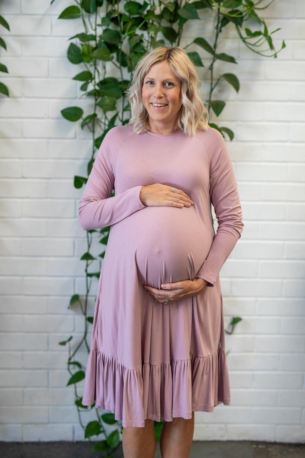 Pregnant lady holding her baby bump in a pink dress