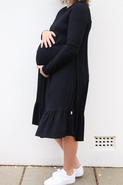 Side of view of a pregnant lady wearing a stylish black maternity dress