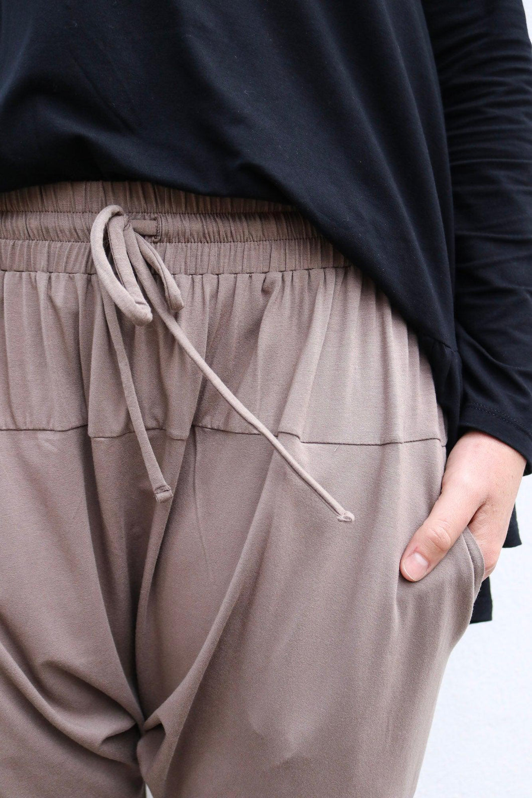 hands in pockets of brown pants and a black top