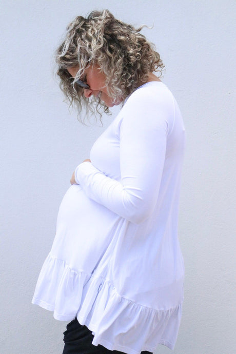 pregnant lady wearing sunglasses in a white long sleeve top with ruffles