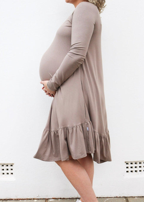 Side view of a pregnant lady holding her baby bump in a dress